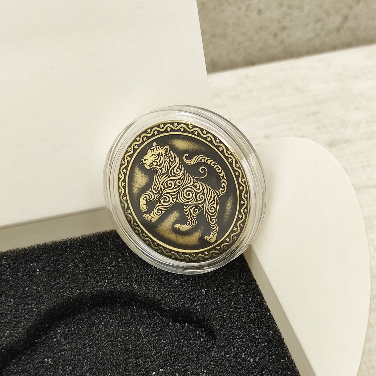 Macro photo of the brass Tiger coin in a protective capsule, highlighting the intricate dark recessed patina engraving for high contrast.